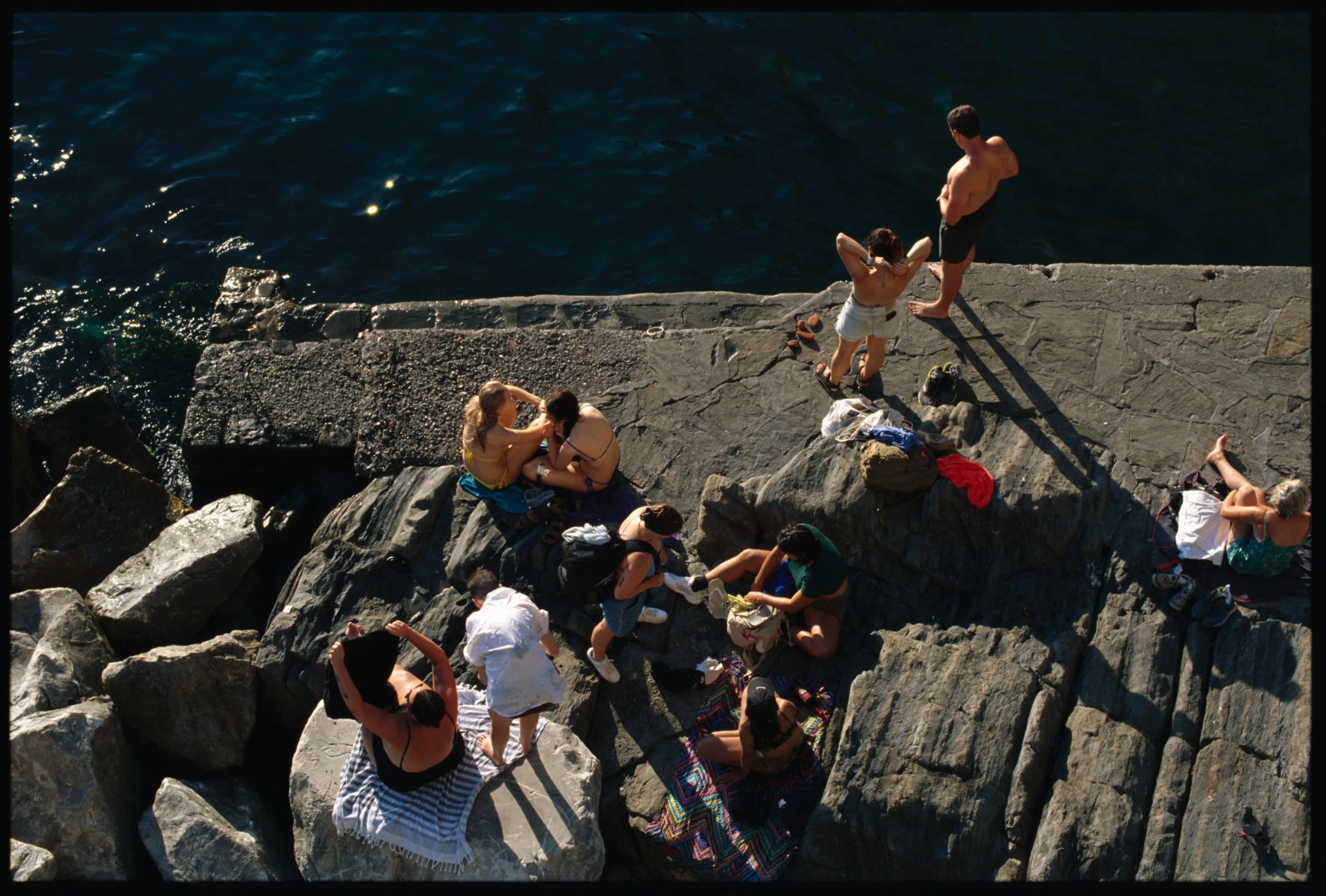 Kodak E100 drum scan showing people on coastal rocks beside deep blue water